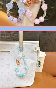 Detail shot of blue beaded charm with Capybara character hanging on a white tote bag.