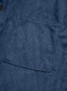 Detailed close-up of navy blue corduroy fabric texture with pocket and button detail