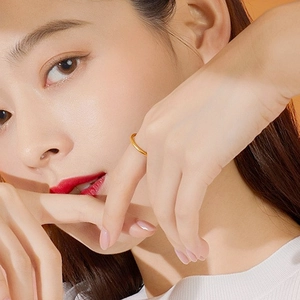 Close-up of a minimalist golden clover ring worn by a model on a warm background