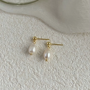 Detailed macro shot of baroque teardrop freshwater pearl earrings on white stone background