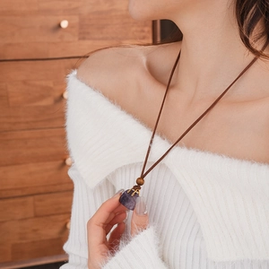 Close-up of a purple faux stone pendant on brown leather cord with a wooden bead