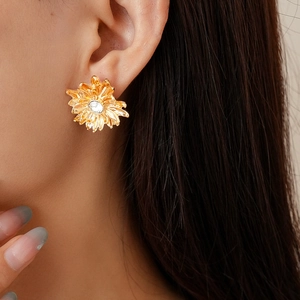 Close-up of vintage golden daisy earring with crystal center worn on model's ear
