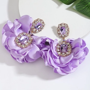 Detail of purple silk camellia earrings with sparkling crystal accents and gold finish