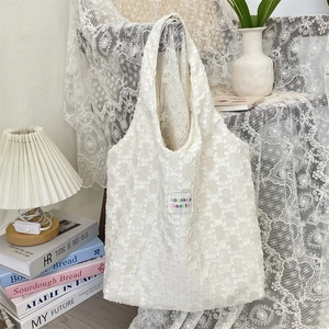 Vue détaillée du sac cabas en dentelle blanche avec fleurs 3D et étiquette tissée vintage
