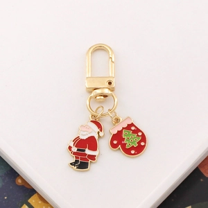 Detail of golden Christmas keychain featuring Santa and enamel glove pendants on a tray