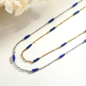 Double-layered gold and silver necklace with blue cylindrical beads on a white background