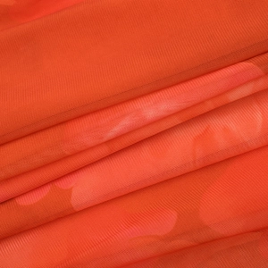 Détail de maille fine orange transparente avec un imprimé floral flou et une texture légère