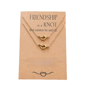 Detail of double knot pendants in 18k gold finish on a gift card for friendship