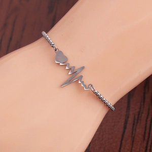Adjustable stainless steel bracelet with heartbeat and heart charm on a model's wrist