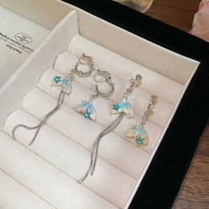 Detail of fishtail earrings with blue gradient lacquer pearls and stars on velvet display