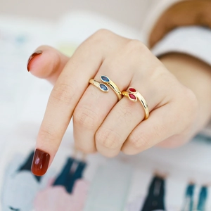 Macro detail of adjustable gold rings with navy blue and red marquise-cut zircon stones