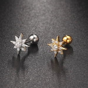 Star-shaped stud earrings in gold and silver with cubic zirconia on black background