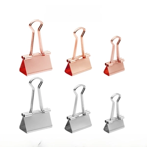 Macro shot of rose gold and silver metal binder clips in small, medium, and large sizes