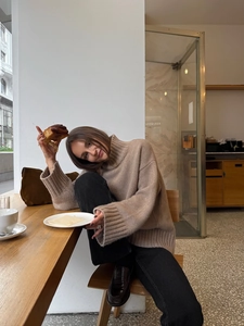 Chic oatmeal turtleneck sweater with thick knit texture styled in a cozy cafe setting