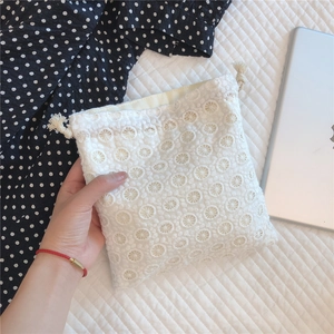 Detail of white lace drawstring pouch with intricate eyelet embroidery and cotton rope
