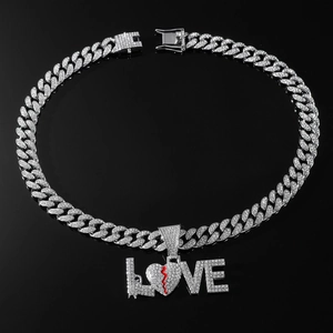 Macro view of iced out LOVE letter pendant with broken heart and gun details on Cuban chain