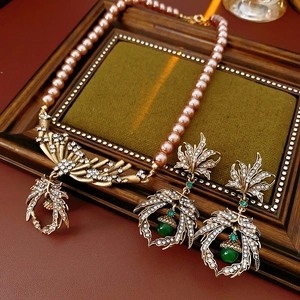 Close-up of vintage jewelry set with pink pearls, golden leaf motifs, and green acorn beads