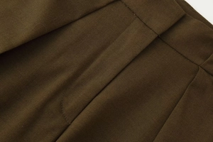 Gros plan détaillé du pantalon plissé marron foncé montrant les coutures et poches