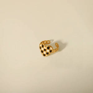 Detail of adjustable golden chain ring featuring a black and white checkerboard heart