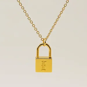 Macro view of gold padlock pendant featuring engraved letter F on a polished surface