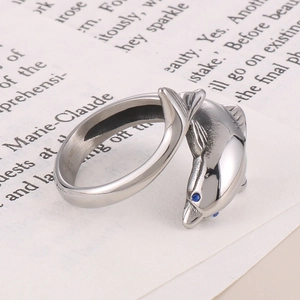 Close-up of a silver dolphin ring with blue eyes on a book page background