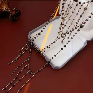Multilayer long necklace featuring black faceted beads and slim gold metal tubes