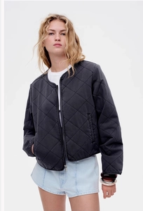 Close-up of black quilted bomber jacket with zipper closure and ribbed round neckline