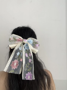 Detail showing delicate floral embroidery on white lace mesh oversized bow hair clip