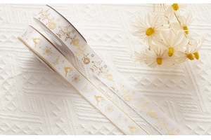 Detailed view of white Christmas ribbons with gold foil patterns of Santa and reindeer