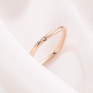 Macro shot of a rose gold square ring featuring a single diamond on white fabric