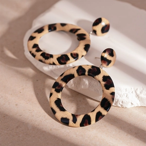Detail of leopard print hoop earrings on stone display with aesthetic sunlight shadows