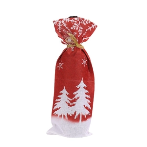 Red burlap Christmas wine bottle gift bag featuring white pine tree and snowflake prints