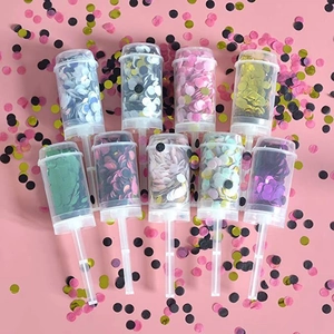Detailed overhead view of 9 multi-color push-pop confetti poppers on pink background
