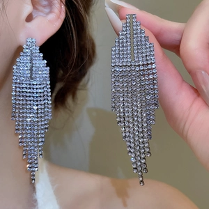 Macro detail of silver tassel drop earrings with sparkling rhinestones worn on ear