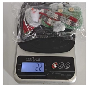Christmas snowman plush knitted ornament being weighed on a scale showing 22 grams