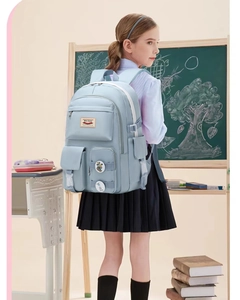 Detail of light blue student backpack with multiple pockets and badges in classroom