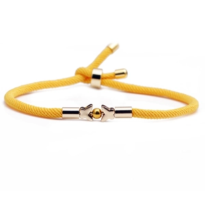 Detailed close-up of yellow braided cord bracelet with gold butterfly charms and slide knot