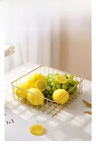 Close-up of a luxury gold wire fruit basket with rectangular mesh on a marble table