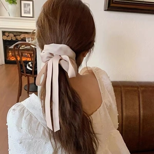 Back view of a large pale pink satin bow scrunchie with long ribbons on a ponytail