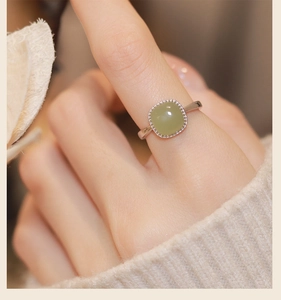 Close-up of a silver ring with a square green jade stone worn on a finger