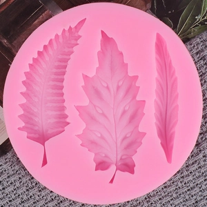 Detail of pink silicone mold featuring intricate fern and maple leaf patterns for DIY baking