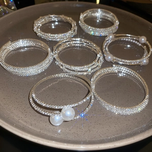 Dettaglio di bracciali elastici multistrato con perle e strass su un vassoio di ceramica