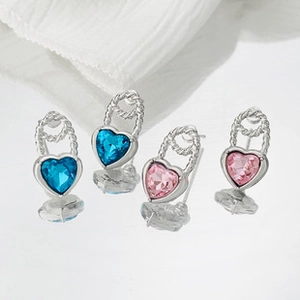 Gros plan de boucles d'oreilles en cristal en forme de cœur bleu et rose sur fond blanc