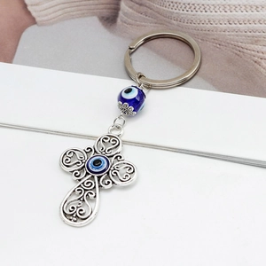 Dettaglio portachiavi croce argento vintage con perline blu malocchio e motivo a filigrana
