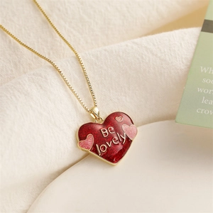 Détail d'un collier doré avec pendentif cœur rouge et gravure Be Lovely sur le bijou