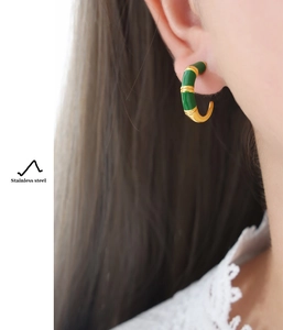 Close-up of gold and green enamel bamboo-shaped stainless steel earrings on a model