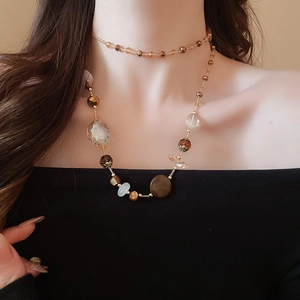 Dettaglio di collana multistrato con perle ambra e inserti in pietra e cristallo
