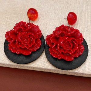 Vue macro de boucles d'oreilles fleurs rouges avec base ronde noire et détails en résine