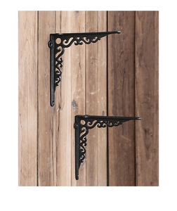 Detail of vintage black cast iron shelf brackets with scrollwork pattern on wood