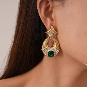Gros plan de boucles d'oreilles vintage dorées avec cristaux et pierre émeraude verte